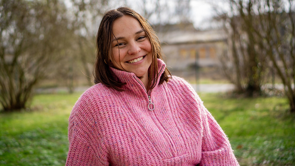 Alexandra Espinosa Rojas sits on a meadow.