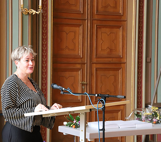 Ute Wunderlich speaks at the podium in front of the audience.